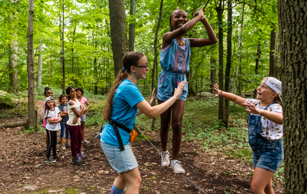 two young girl scouts outside at state park using binoculars - older girl is helping daisy girl scout see nature