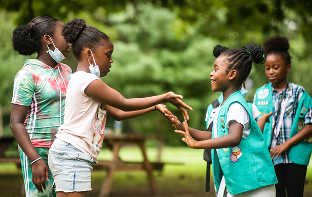 young girl scout outside cheering with hands in the air